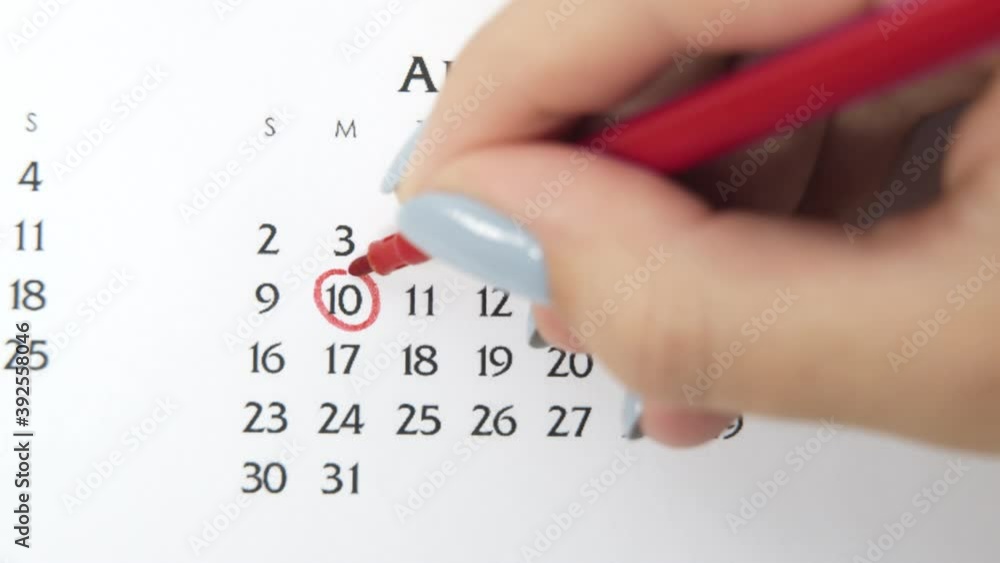 Female hand circle day in calendar date with a red marker. Business Basics Wall Calendar Planner and Organizer. August 10th Female hand circle day in calendar date with a red marker. Business Basics Wall Calendar Planner and Organizer. August 10th