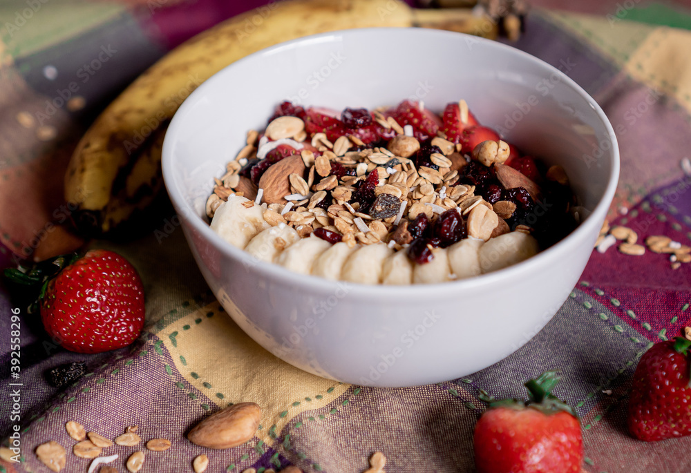 Delicious oatmeal with banana, strawberries, granola, blueberry, coconut and almonds on top, inside a white plate. Delicious oatmeal with banana, strawberries, granola, blueberry, coconut and almonds on top, inside a white plate.