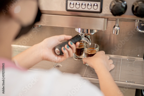 Barista serving coffee with a coffee maker in two small glasses