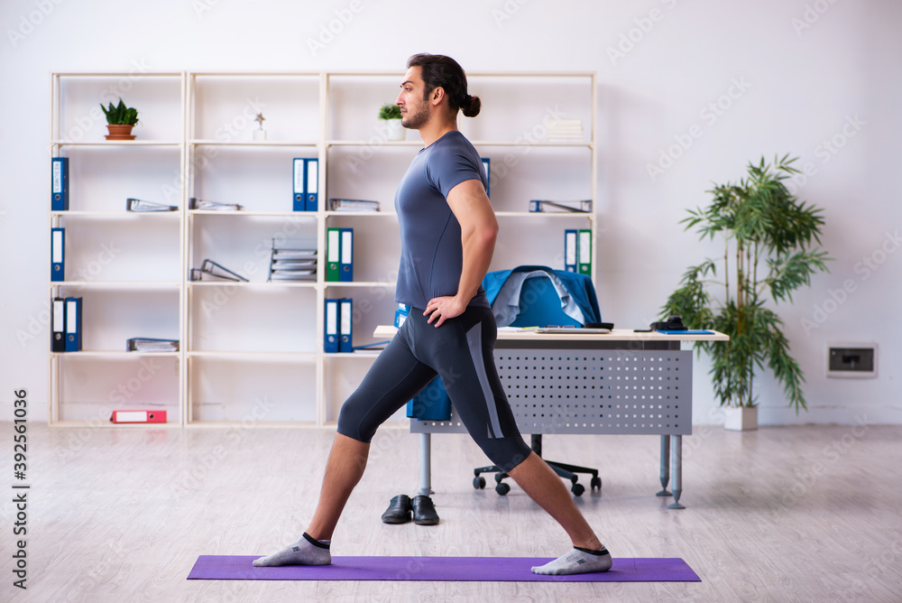 Young handsome employee doing sport exercises in the office Young handsome employee doing sport exercises in the office