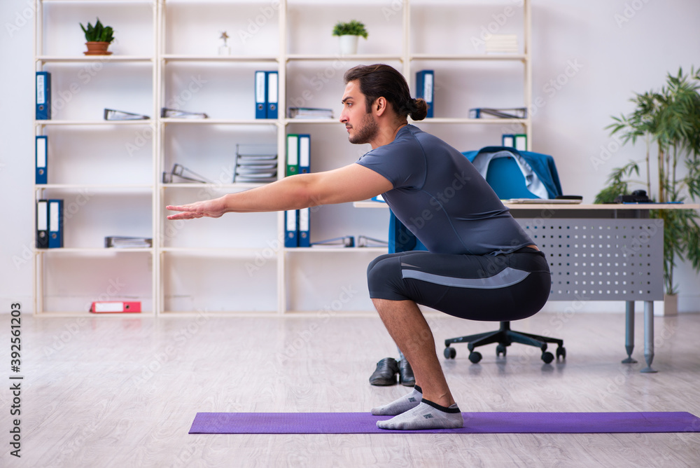 Young handsome employee doing sport exercises in the office Young handsome employee doing sport exercises in the office