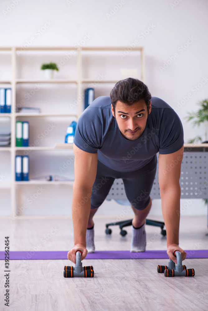Young handsome employee doing sport exercises in the office Young handsome employee doing sport exercises in the office