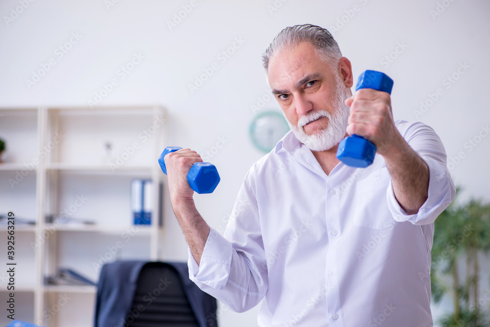 Aged male employee doing physical exercises during break Aged male employee doing physical exercises during break