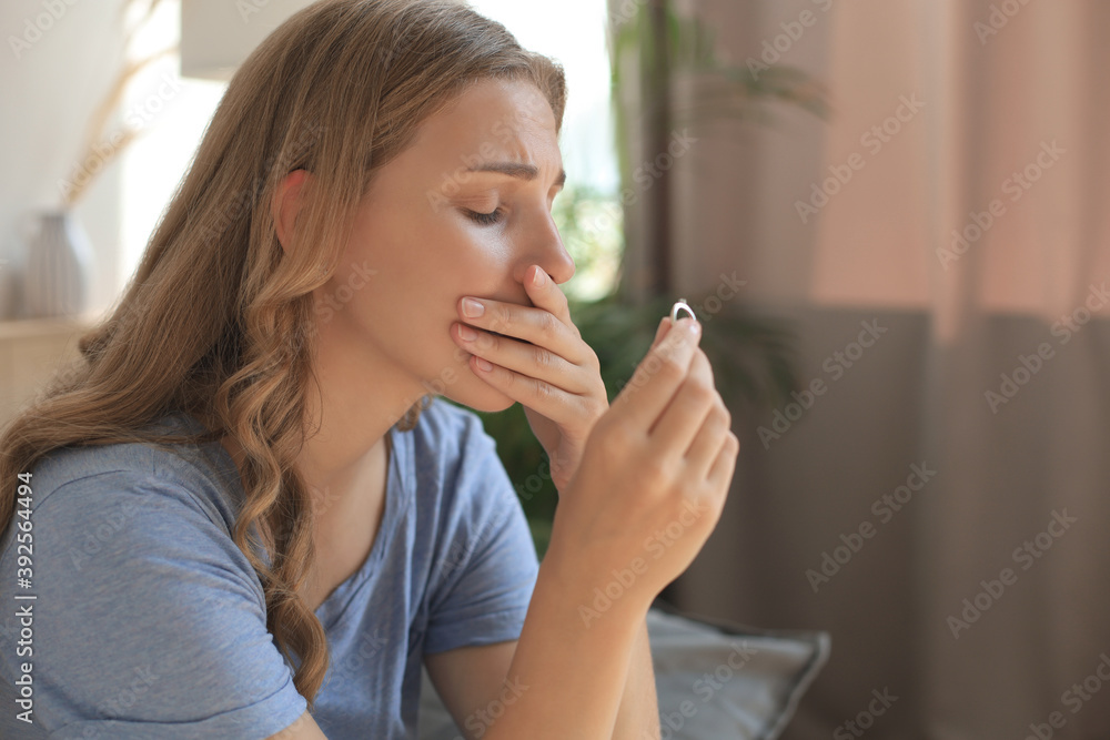 Sad woman sitting on a sofa in the living room. Sad woman sitting on a sofa in the living room.