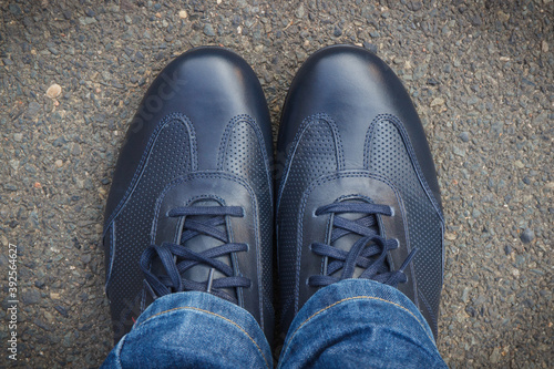 Comfortable navy blue leather shoes for men on asphalt road or footpath. Male footwear