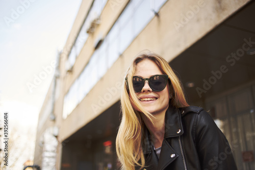 Fashionable woman in sunglasses blond building leather jacket