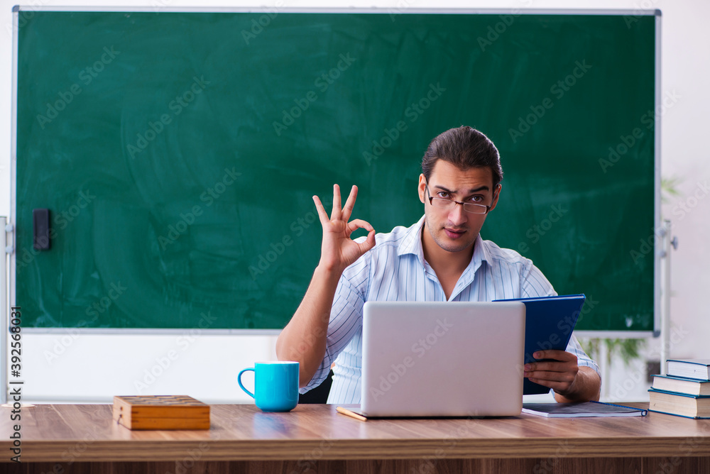 Young male teacher in front of blackboard Young male teacher in front of blackboard