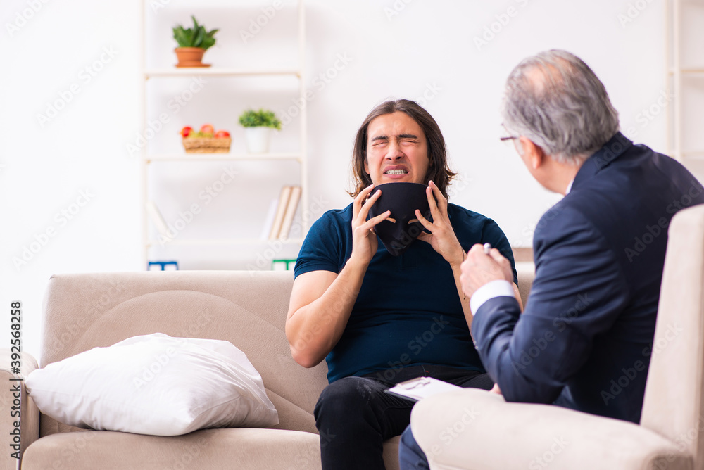 Young man wearing masks during psychotherapy session Young man wearing masks during psychotherapy session