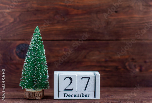 December 27 on the calendar.Calendar with a small Christmas tree on a wooden background. Winter. Empty space for text. photo