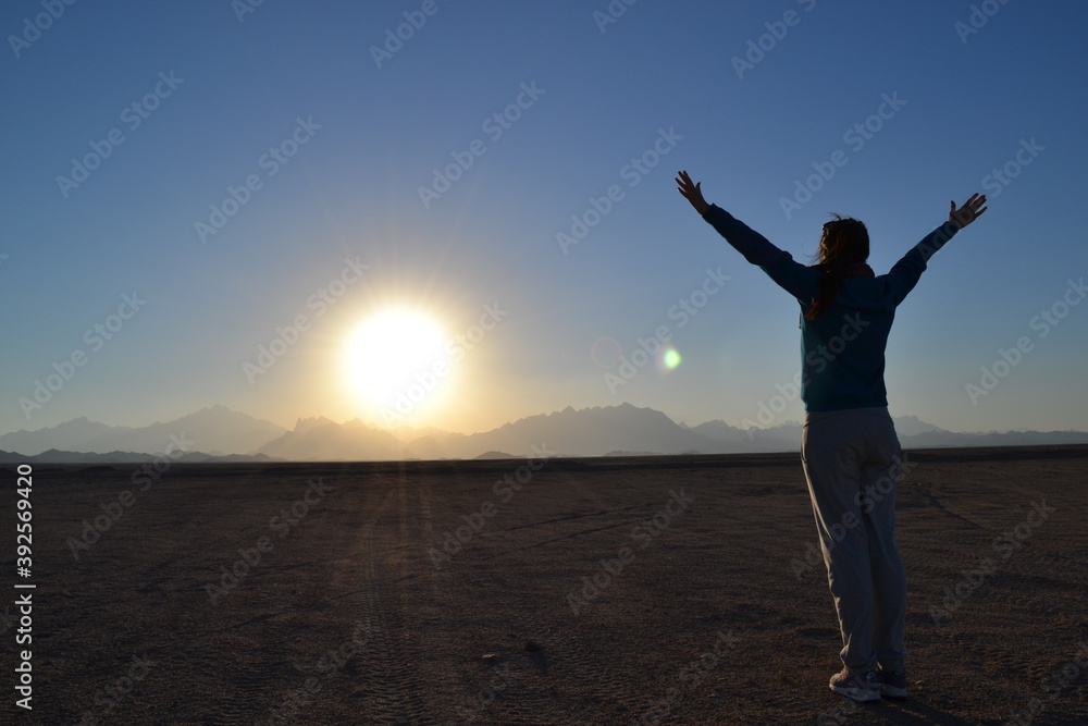 Girl on the background of the sun in the desert