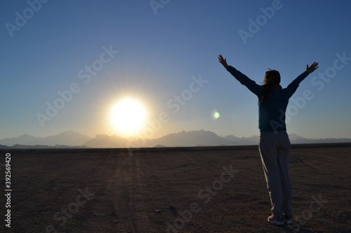 Girl on the background of the sun in the desert