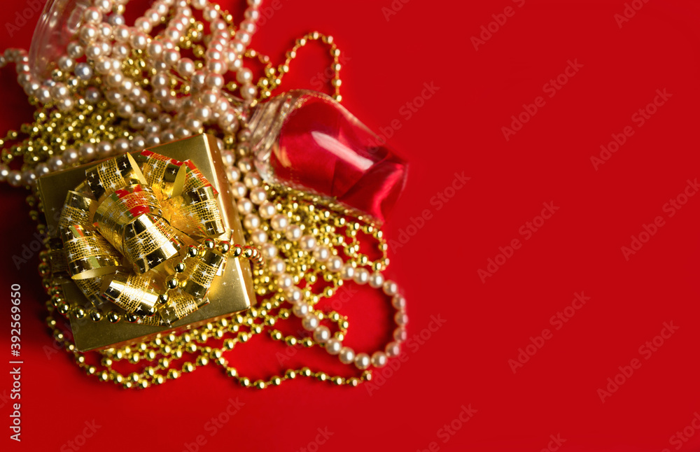 .Gold box with a glass in pearl beads on a red background. Christmas gift concept.. Close-up. Selective focus. Place for text.