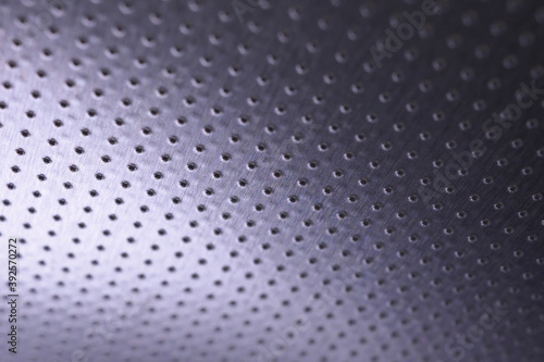 Dark metal wallpaper. Tinted violet or purple background. Perforated aluminum surface with many holes, hanging from above like a ceiling. Perforation rows go into the distance and form perspective