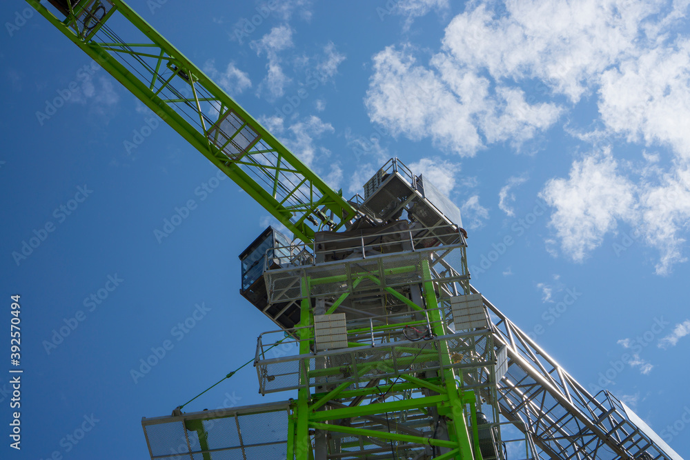 Upward view of Tower Crane, silver and green color on long steel beam arm 