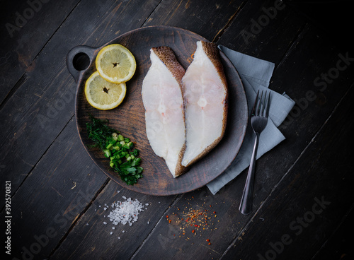 Frozen Greenland halibut steaks on the wood cutting board. Food background. Top view photo