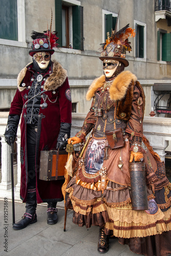Couple wearing ornate matched carnival costumes posing for picture by city background
