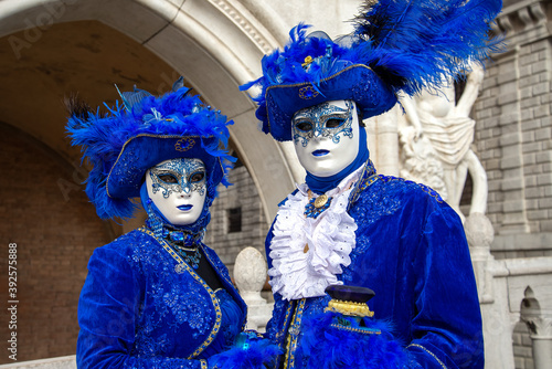 Couple wearing ornate matched carnival costumes posing for picture by city background © Gioia