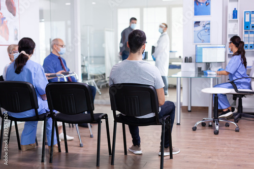 Modern clinic reception and waiting area with patients wearing face mask as safety precaution against coronavirus. Social distancing, medic, covid-19, man, worried, protection, corona,