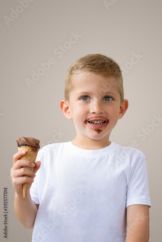 Baby boy kid hold chocolate ice cream in waffles cone isolated on beige background with free text copy space