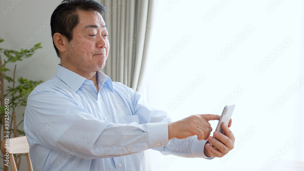 スマートフォンを使う老眼の中年男性 スマートフォンを使う老眼の中年男性
