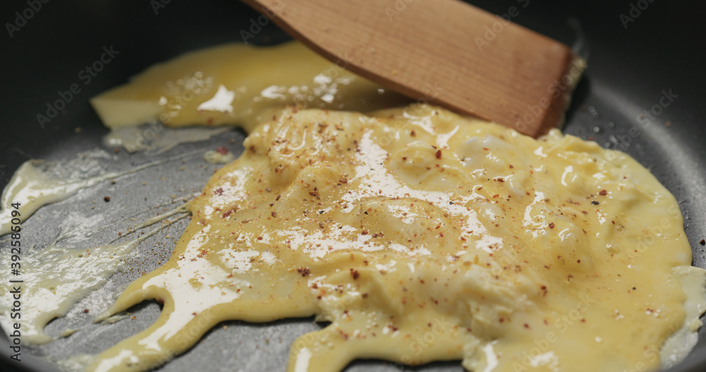 making scrambled eggs on nonstick pan, mixing with wooden spatula making scrambled eggs on nonstick pan, mixing with wooden spatula
