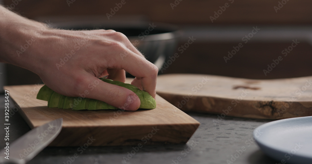 Slow motion man slicing avocado on olive wood board Slow motion man slicing avocado on olive wood board