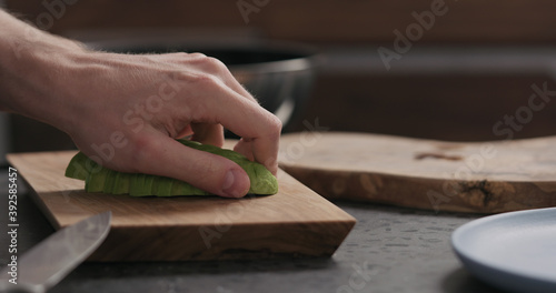 Slow motion man slicing avocado on olive wood board