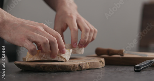 Slow motion man makes sandwich with avocado and cream cheese on olive board