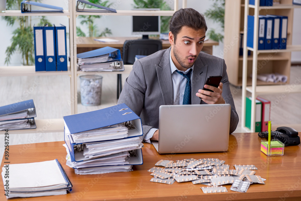 Young male sick employee suffering at workplace Young male sick employee suffering at workplace