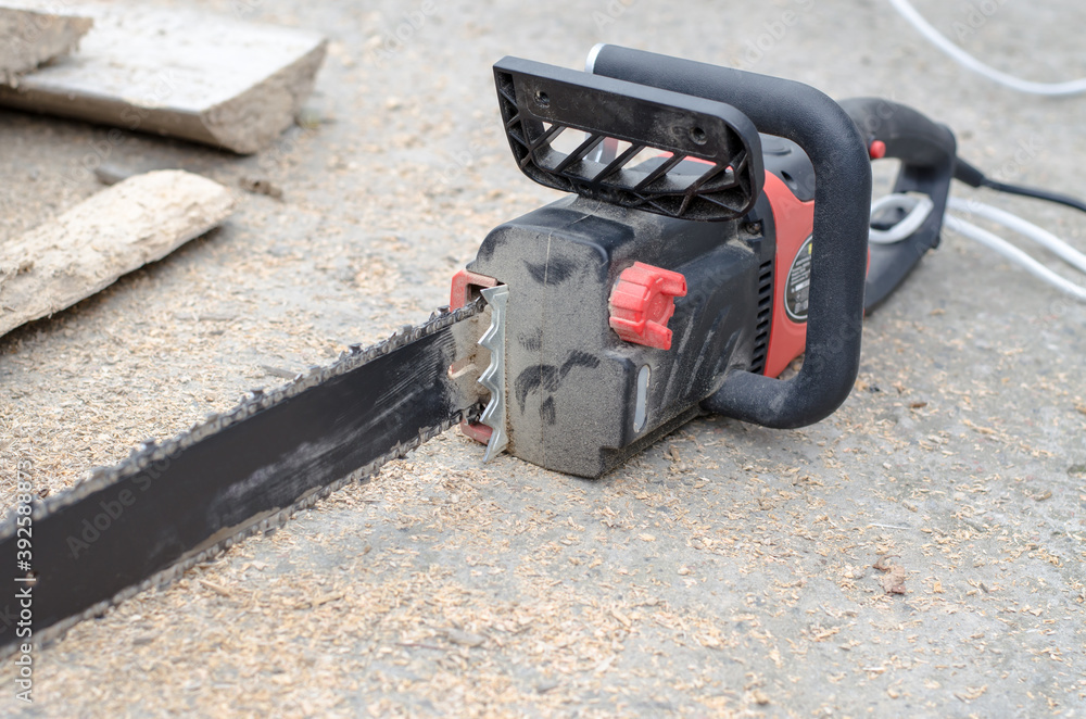 Black hand power saw lies near the firewood Black hand power saw lies near the firewood