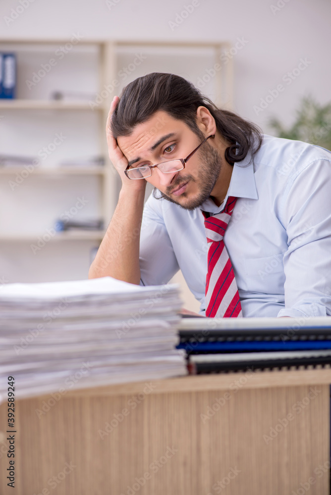Young male employee unhappy with excessive work Young male employee unhappy with excessive work