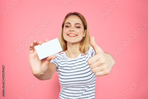 woman striped t-shirt business card in hands emotions pink background copy space