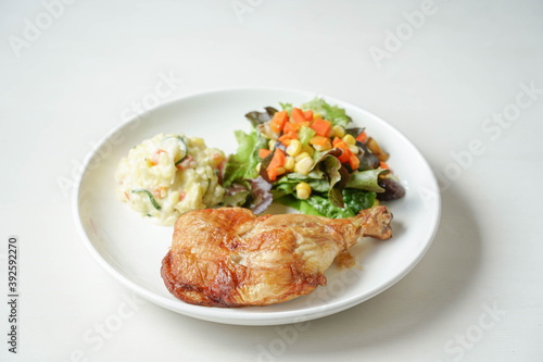plate of delicious grilled chicken legs steak with vegetable and salad potato on white background