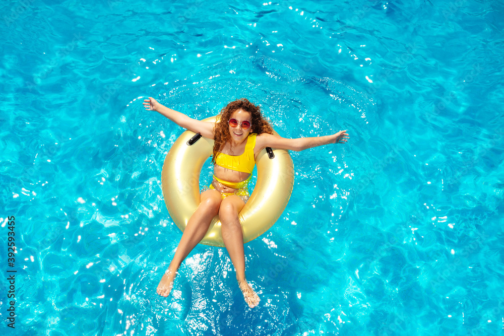 Beautiful teen girl swim in pool on inflatable doughnut view from above with hands apart and big smile