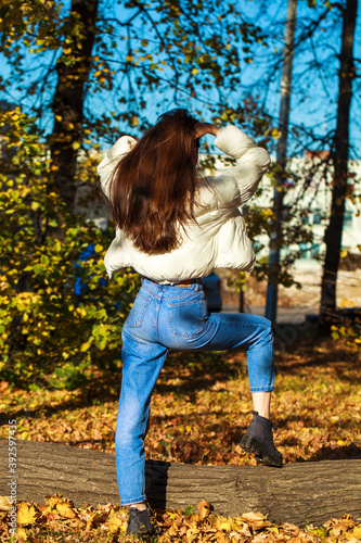 Young beautiful brunette girl in blue jeans, autumn park outdoor