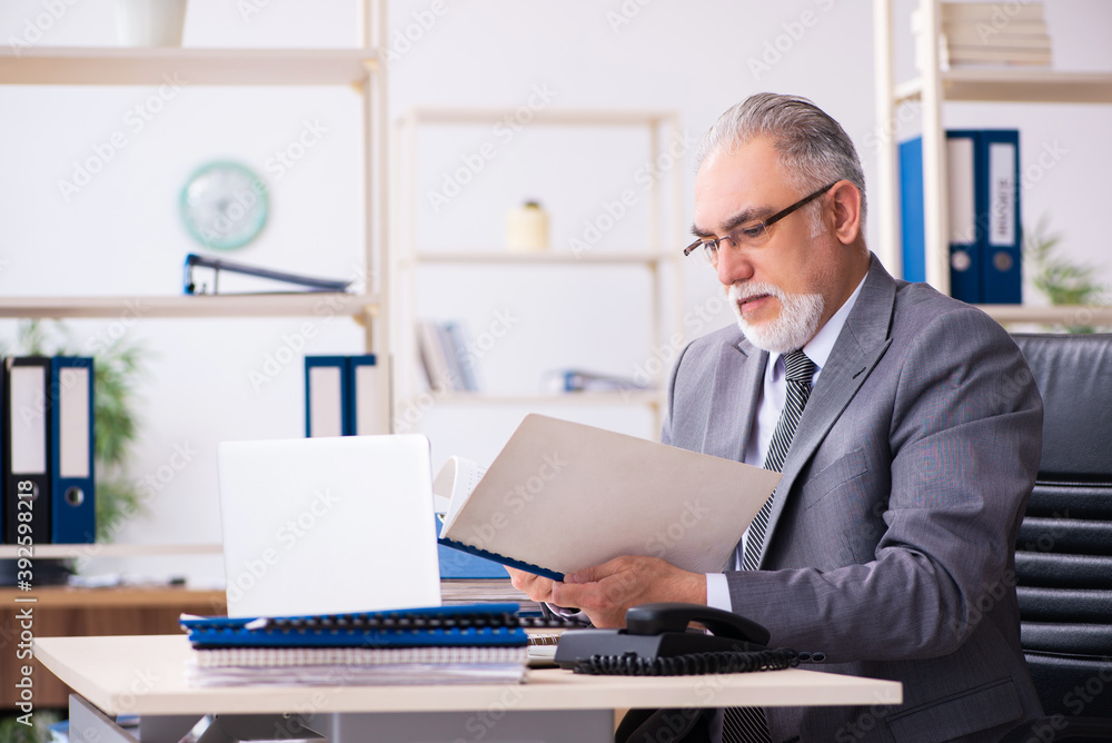 Old male employee and paperwork in the office