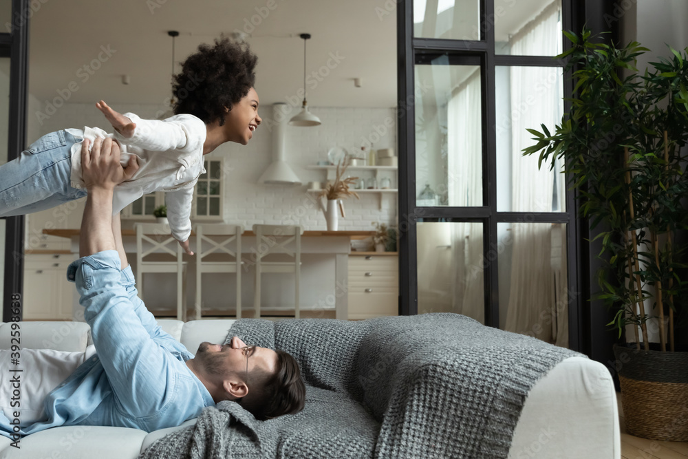 Caring Caucasian young father carrying African American little girl