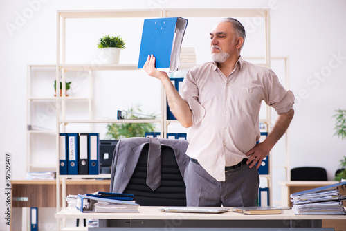 Old male employee doing physical exercises at workplace