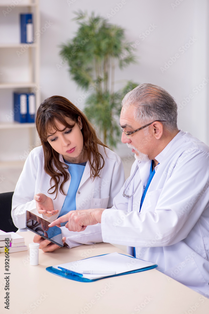 Old male doctor radiologist and his young female assistant in th Old male doctor radiologist and his young female assistant in th