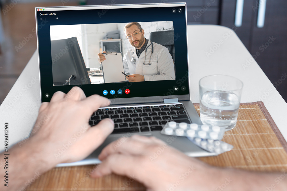 Close-up view of a patient's hand in front of a laptop during an online consultation with a doctor. Close-up view of a patient's hand in front of a laptop during an online consultation with a doctor.