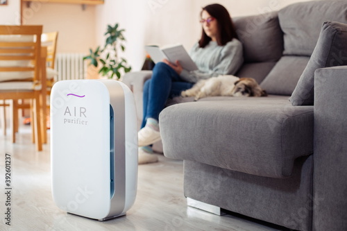 Woman at home reading on the sofa with her pet in a clean and safe environment from virus by air purifying filter.