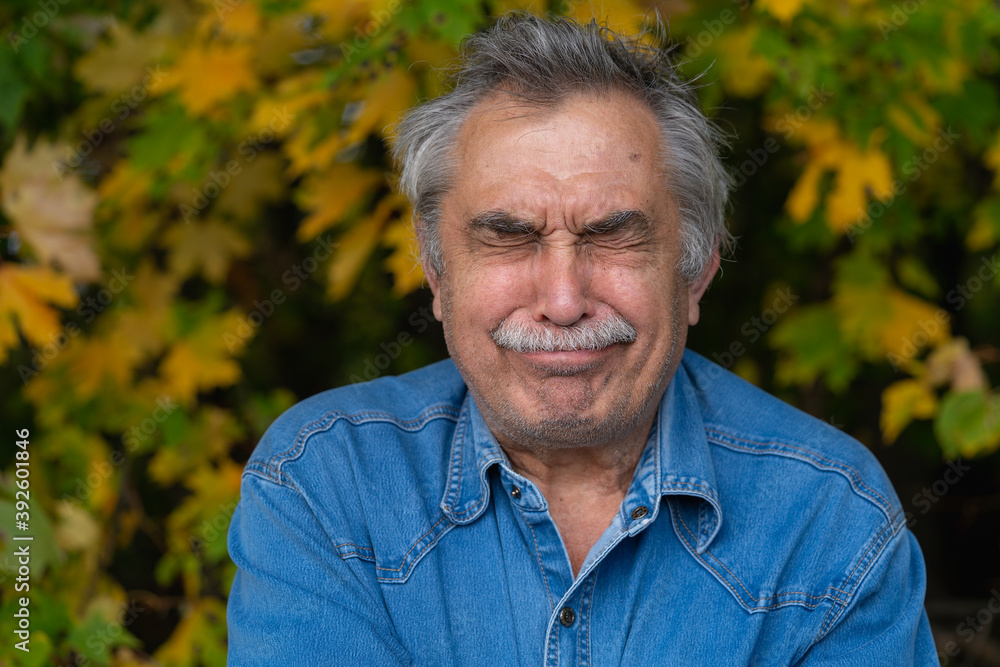 Portrait of a 70-year old elderly man who closed his eyes, but he barely suppresses laughter. Portrait of a 70-year old elderly man who closed his eyes, but he barely suppresses laughter.