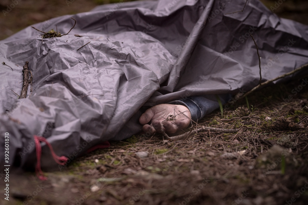 Dead man body In the woods. Caucasian man body covered with sheet . Dead man hand. Murder in the woods Dead man body In the woods. Caucasian man body covered with sheet . Dead man hand. Murder in the woods