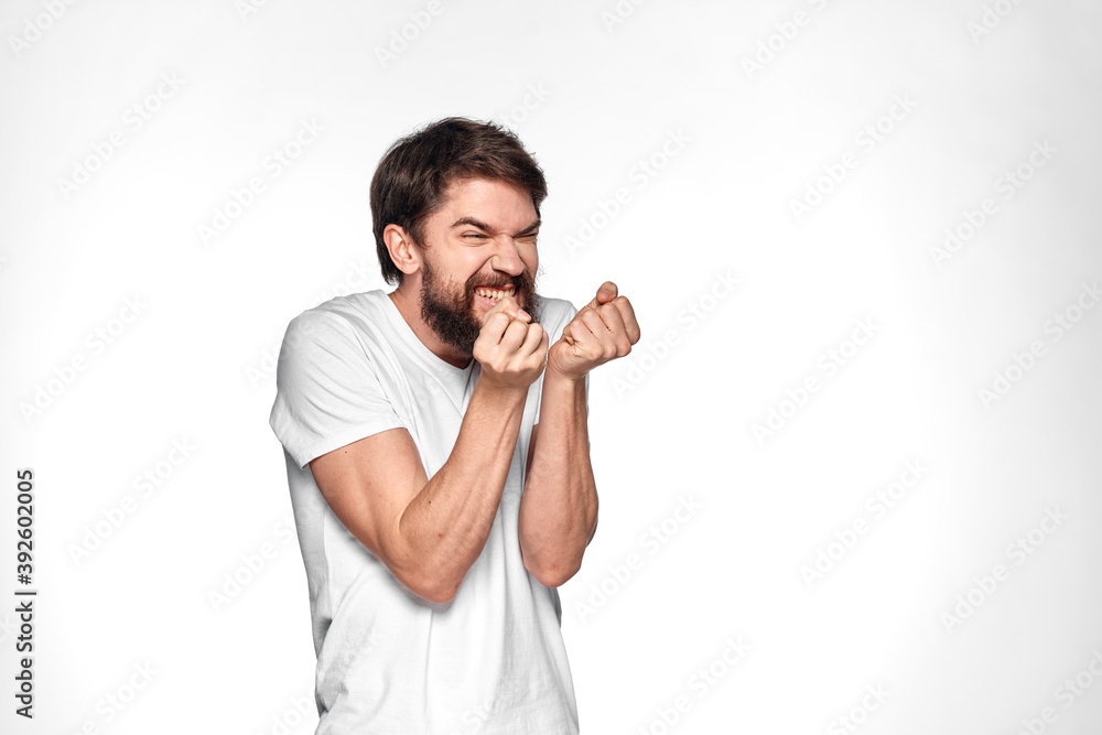 Bearded man in white t-shirt gesture with hands emotions light background Bearded man in white t-shirt gesture with hands emotions light background