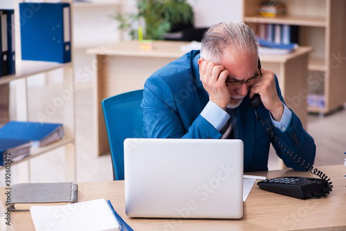 Old male bookkeeper unhappy with excessive work at workplace