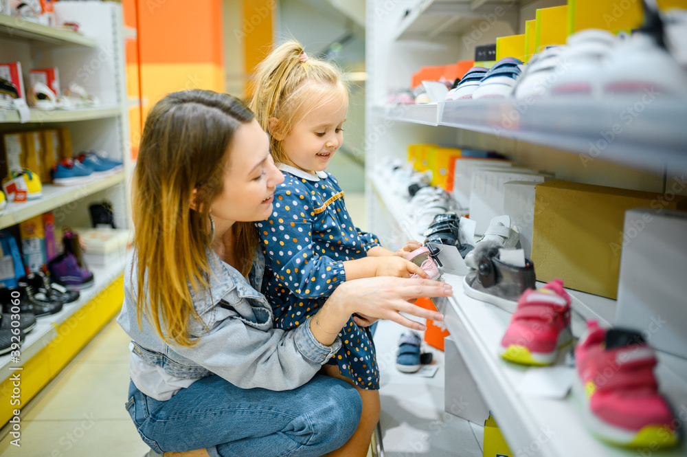 Mother and baby looking on shoes in kid's store