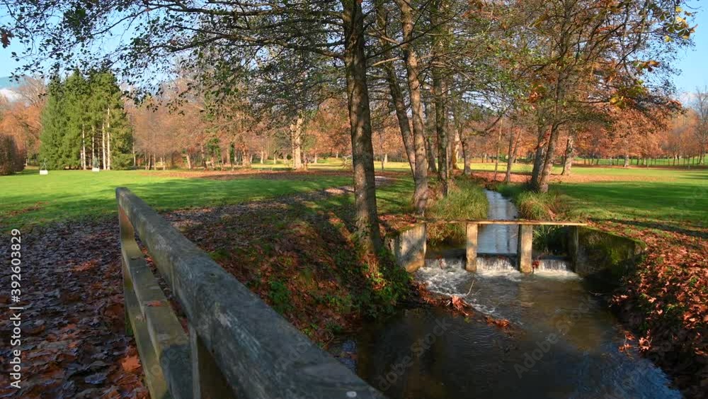 Small stream flows in beautiful nature in park Brdo, Slovenia, government venue for diplomatic meetings. Colorful autumn season on bright sunny day. Wide angle, left pan, real time Small stream flows in beautiful nature in park Brdo, Slovenia, government venue for diplomatic meetings. Colorful autumn season on bright sunny day. Wide angle, left pan, real time