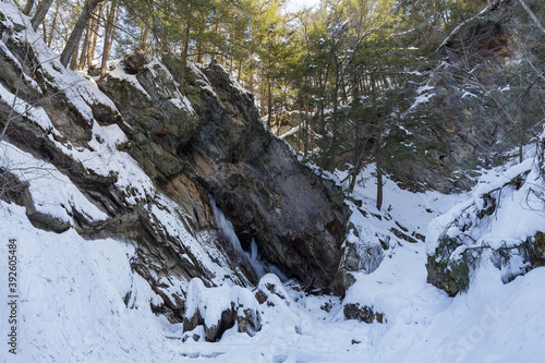 Moss Glen Falls in winter after snow storm. Water turned into ice and is covered with a snow. Bright sunny day.