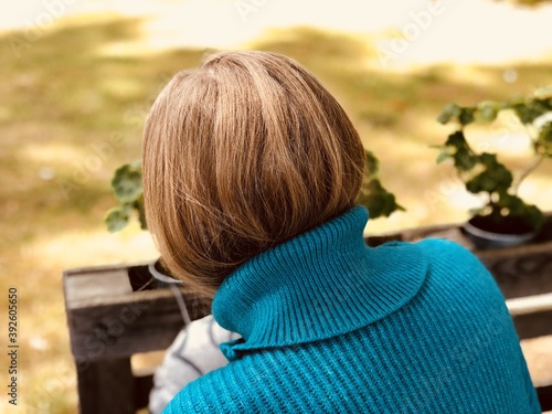 a woman wearing a blue sweater from the back looking at plants