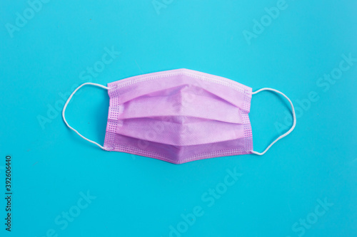 Pink protective medical mask on blue background. Top view